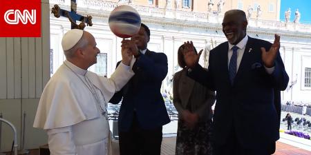 البابا لاوُن يُدير كرة سلة على إصبعه خلال استقبال فريق "هارلم غلوبتروترز" الاستعراضي